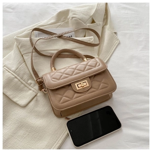 Détail du mini sac matelassé kaki avec fermoir doré à côté d'un smartphone