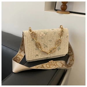 Détail du sac tissé beige avec broderie florale et chaîne en acrylique ambré sur cuir
