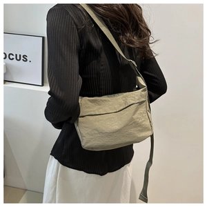 Green nylon crossbody bag with textured fabric and wide shoulder strap shown on model