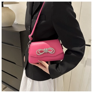 Detail view of pink crossbody bag with sparkling silver rhinestone bow decoration