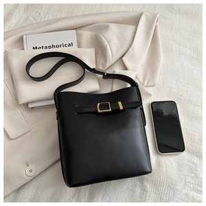 Close-up of black matte leather bucket bag with decorative golden metal buckle