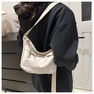 Detail of minimalist beige canvas crossbody bag with adjustable strap on model