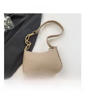 Detail of beige crocodile embossed texture on a chic shoulder bag with gold metal chain