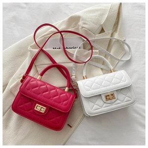 Détail de sacs matelassés rose et blanc avec fermoir doré posés sur un blazer beige