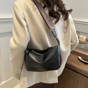 Fashionable black faux leather dumpling crossbody bag with woven shoulder strap and gold logo