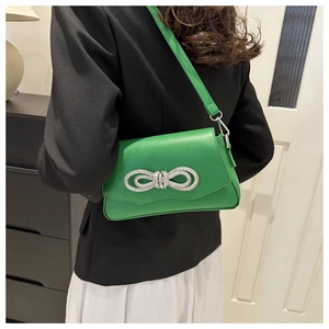 Detailed view of bright green shoulder bag with silver rhinestone bow and PU leather texture