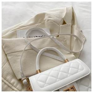 Détails d'un sac à main blanc matelassé avec fermoir doré et bandoulière amovible