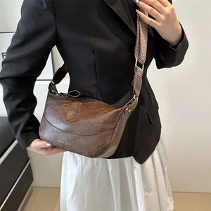 Dark brown pebbled leather half-moon crossbody bag with wide herringbone strap