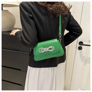 Detail of green crossbody bag featuring a sparkling silver rhinestone bow decoration