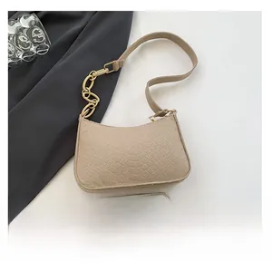 Detail view of beige crocodile pattern handbag with gold chain strap and phone for size