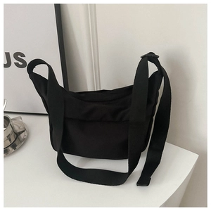 Minimalist black crescent crossbody bag with wide adjustable strap in modern home setting