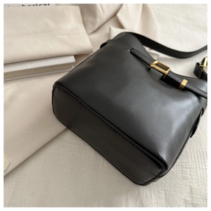 Detail shot of black matte leather shoulder bag with elegant gold metal buckle hardware
