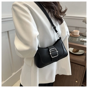 Vue latérale d'un sac baguette noir avec une grande boucle argentée porté par un modèle