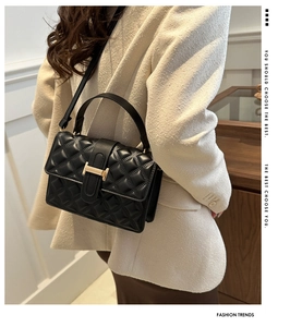 Detail of black quilted leather crossbody bag with golden H clasp on model