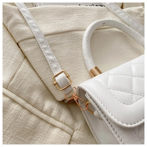 Détail d'un sac à main blanc matelassé avec des finitions dorées et des coutures fines