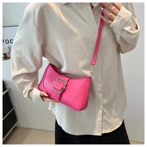 Vue détaillée d'un sac baguette rose vif avec une grande boucle argentée porté en travers