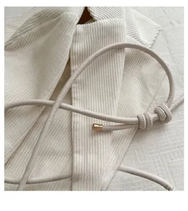 Detail of minimalist beige PU shoulder strap with gold metal tips and knot detail