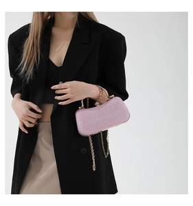 Pink glitter clutch bag with gold handle and chain strap carried by a woman