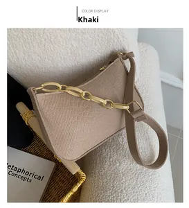 Detail of khaki faux crocodile shoulder bag with chunky cream chain on soft sofa