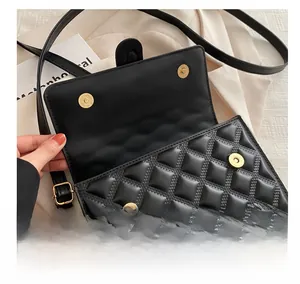 Detail shot of the black quilted crossbody bag showing golden magnetic snap closures