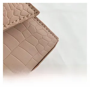 Detailed close-up of pink faux leather bag with crocodile texture and fine stitching