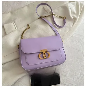 Détail d'un petit sac carré lavande avec boucle dorée vintage sur texture blanche