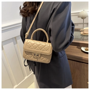 Petit sac bandoulière beige à surpiqûres matelassées présenté dans un cadre d'intérieur chic