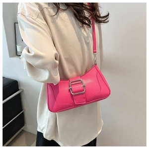 Détail du sac baguette en cuir rose avec une grande boucle carrée en métal argenté sur la bandoulière