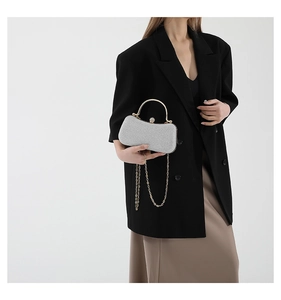 Detail of silver glitter evening clutch with gold handle and jewel clasp on model