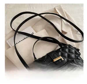 Detail of black quilted crossbody bag featuring a golden H-shaped clasp and adjustable strap