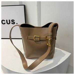 Detail of a deep brown bucket bag with a golden square buckle and fixed shoulder strap