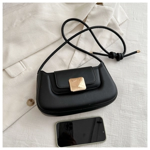 Detail view of a black faux leather shoulder bag with a gold buckle and phone for size reference