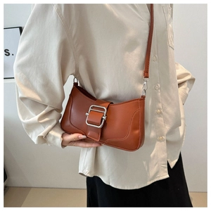 Détail du sac baguette marron caramel avec boucle argentée porté par un mannequin