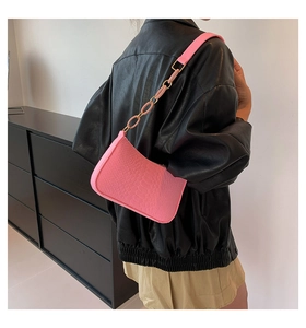 Pink faux crocodile leather shoulder bag with thick chain strap shown on model shoulder