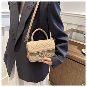 Détail du petit sac beige matelassé avec fermoir rotatif doré et poignée élégante