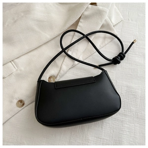 Top view of minimalist black PU leather baguette bag with knotted strap on corduroy