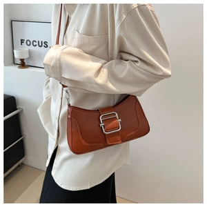Vue détaillée du sac baguette en cuir marron foncé avec boucle argentée sur la bandoulière