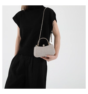 Pochette à paillettes argentées avec poignée dorée et fermoir en strass sur modèle