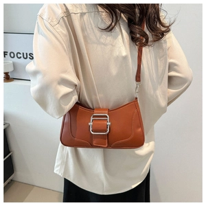 Détail d'un sac bandoulière marron caramel avec boucle argentée porté par un mannequin