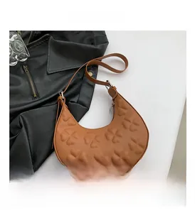 Detail of caramel half-moon bag with embossed clover patterns and smooth zipper
