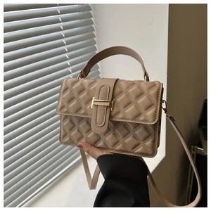Close-up of beige quilted crossbody bag with gold H-buckle and elegant handle