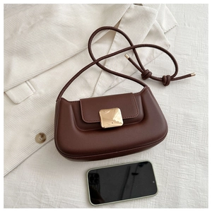 Detail of dark brown faux leather bag with large gold buckle on striped blazer background
