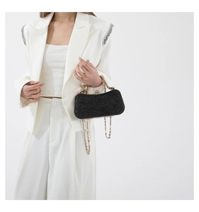 Detail of black glitter evening bag with gold metal frame and rhinestone lock