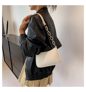 Detail of white crocodile-embossed underarm bag with stylish resin chain strap