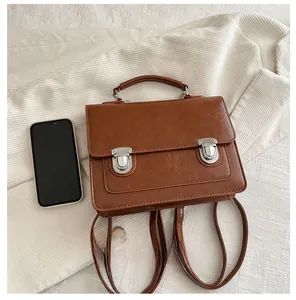 British style brown leather convertible backpack showing size comparison with a phone