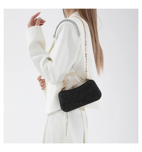 Detail of black glitter evening clutch with golden metal handle and delicate chain strap