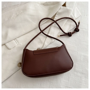 Detail shot of the dark brown half-moon underarm bag on soft white corduroy fabric