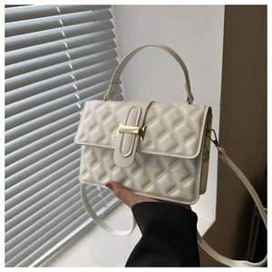 Close-up of white quilted PU leather handbag with elegant gold H-shaped metal buckle