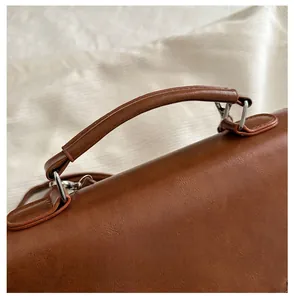 Close-up of the vintage brown faux leather texture with top handle and silver hardware
