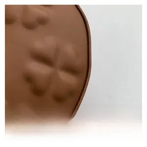 Close-up of textured brown leather handbag with embossed floral pattern detail